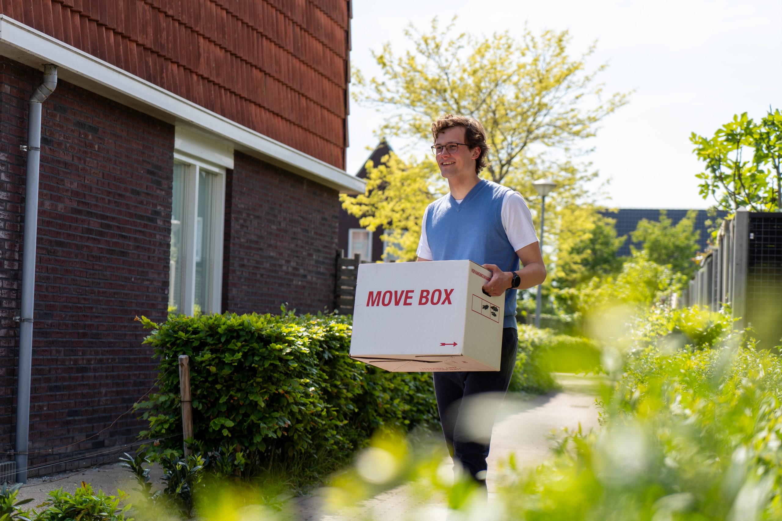 Jongvolwassen man loopt met verhuisdoos